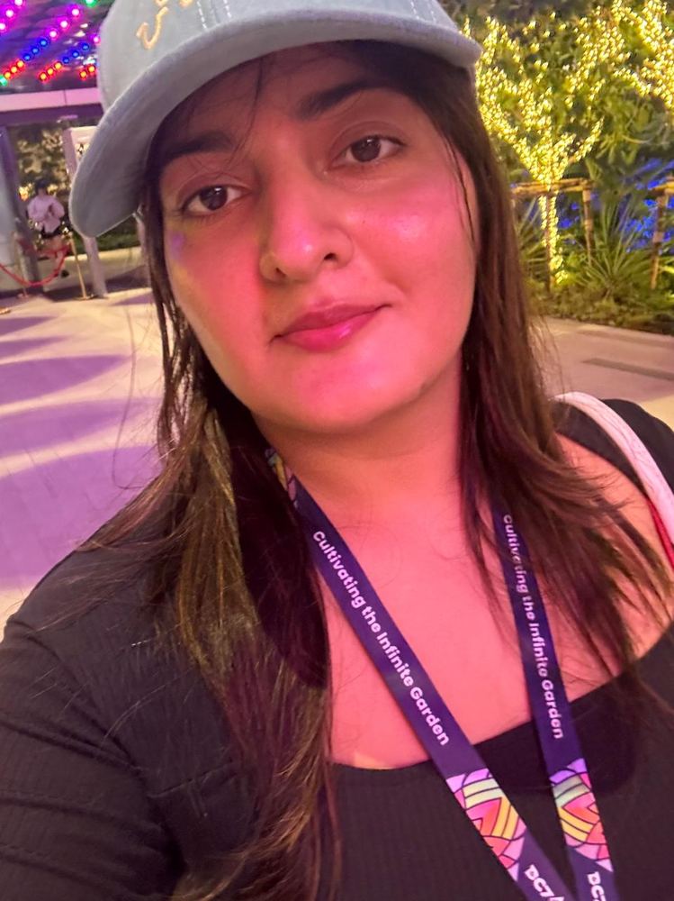 Ruhi in a cap with a Devcon lanyard under festive lights