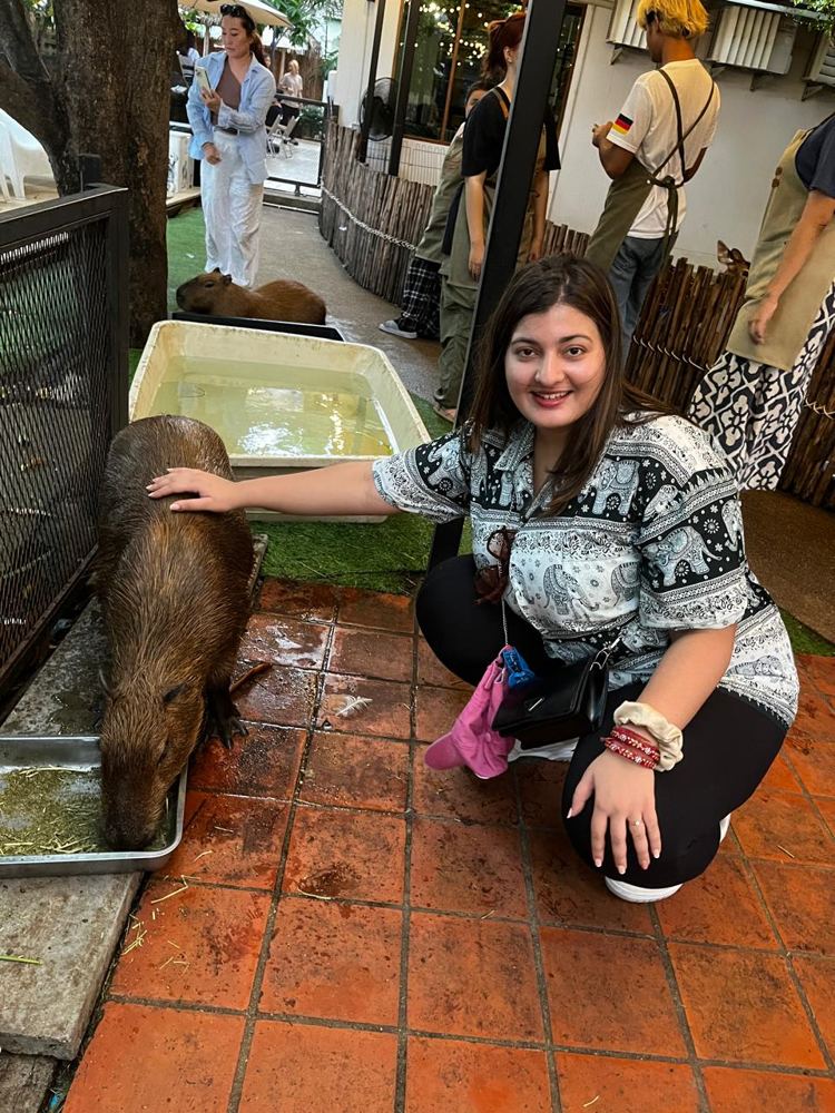Ruhi petting a capybara at a café